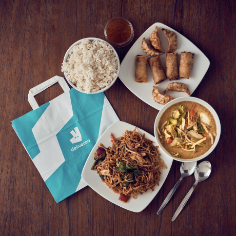 Una borsa di Deliveroo con alcuni piatti intorno