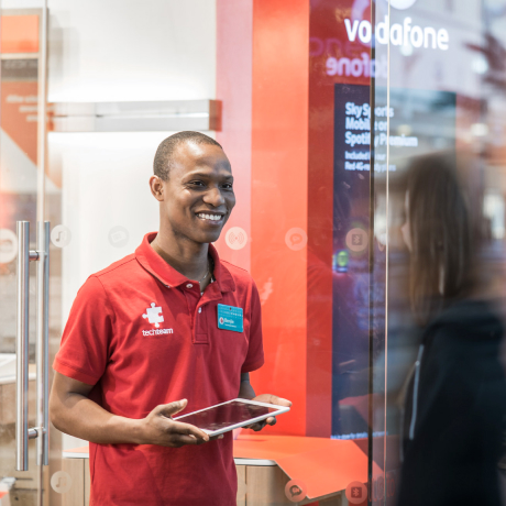 Un dipendente Vodafone utilizza un iPad per assistere un cliente in un negozio.