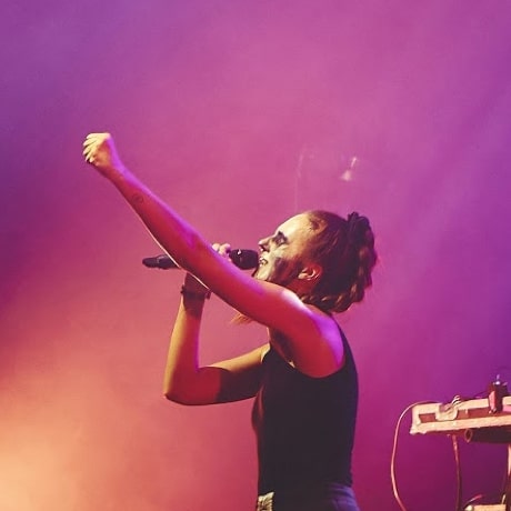 Une chanteuse en concert qui lève le bras avec émotion