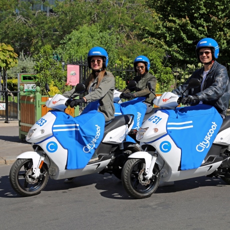Une illustration de 3 personnes conduisant des scooters Cityscoot.